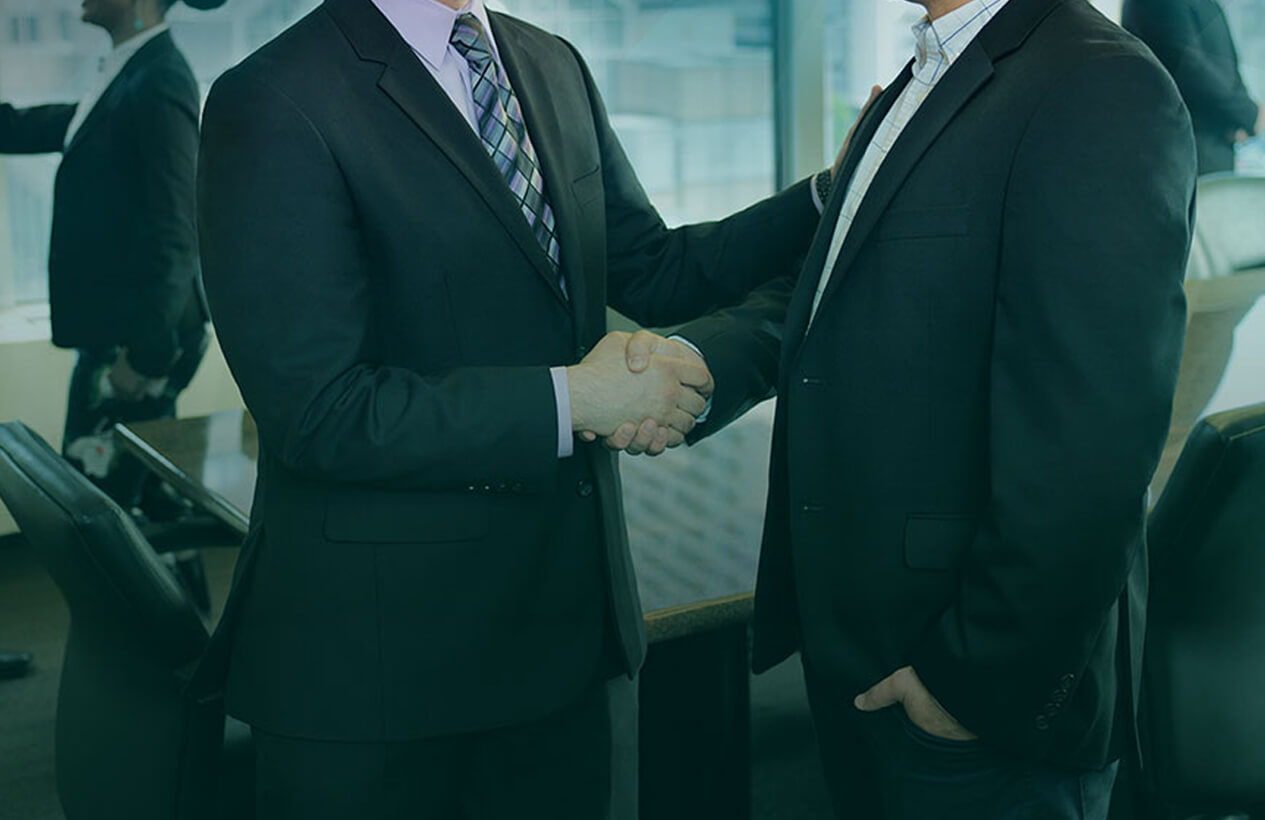 Two professionals shake hands in a modern conference room